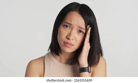 Young Upset Asian Woman Looking Guilty At Camera Over White Background. Sad Expression