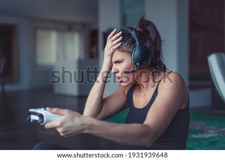 Young upset gamer woman with headset make a mistake when playing online, facepalm