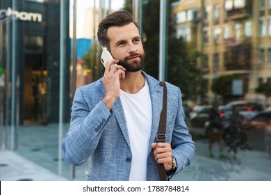 Young urban businessman on smart phone walking in street, talking on smartphone, wearing jacket - Shutterstock ID 1788784814