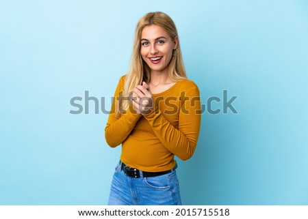 Young Uruguayan blonde woman over isolated blue background laughing