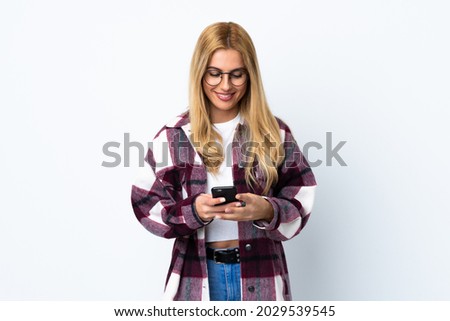 Young Uruguayan blonde woman over isolated white background sending a message with the mobile