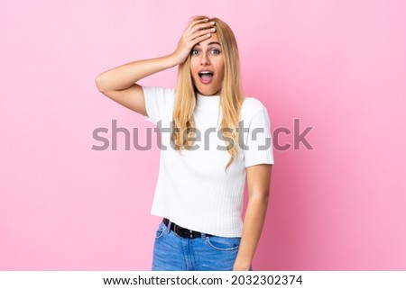 Young Uruguayan blonde woman over isolated pink background doing surprise gesture while looking to the side