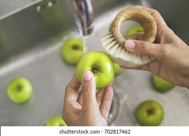 Young Vegan Girl Washing Green Apples with Bamboo Brush. Hand Holding Fresh Fruits Under Running Water in Kitchen Sink. Healthy Lifestyle Hygiene Concept.
