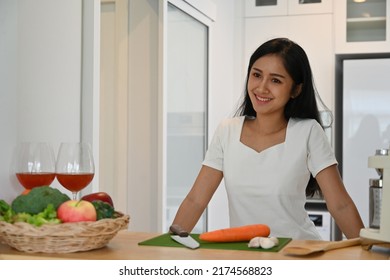 Young Vegetarian Asian Woman In Casual Clothes With Vegetables On The Counter Bar In The Kitchen At Home, Domestic Life And Healthy Lifestyle Concept.