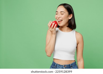 Young vegetarian woman wear white clothe s hold in hand biting ripe red apple close eyes isolated on plain pastel light green background. Proper nutrition healthy fast food unhealthy choice concept - Powered by Shutterstock