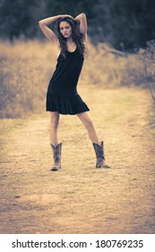 Young Very Thin Girl Posing Outdoors In A Black Dress And Boots