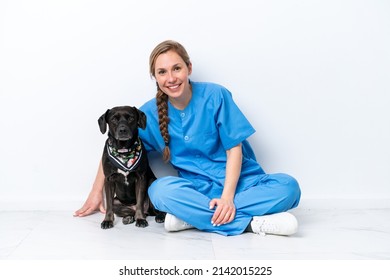 Young Veterinarian Woman With Dog Sitting On The Floor Isolated On White Background With Happy Expression