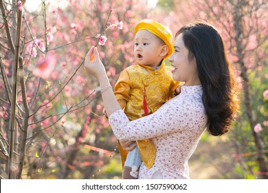 Young Vietnamese Mother With Her Son In Traditional Costume In Peach Flower Garden