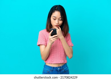 Young Vietnamese woman isolated on blue background thinking and sending a message - Shutterstock ID 2170824229