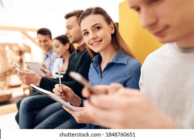 Young vigorous woman records results of exploring mobile application in notebook. Young tester writes his observations on testing interface of new application.