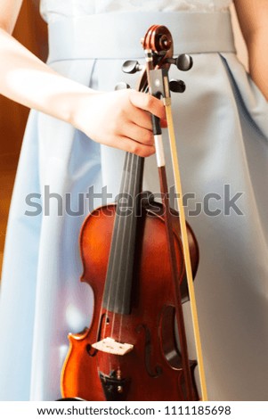 Young violinist blue dress holds violin fiddlestick.