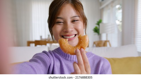 Young vlogger asia people influencer girl take photo eat bite smiley donut funny face post review on   reel app Sweet tooth food sugar lover enjoy fun show viral video camera at home - Powered by Shutterstock