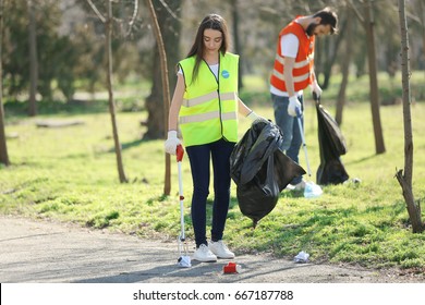 Young volunteer picking up litter in park - Shutterstock ID 667187788