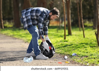 Young volunteer picking up litter in park