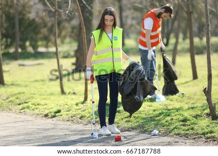Young volunteer picking up litter in park