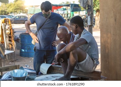 Young Volunteer In A Poor Neighborhood Talking With The People From The Community