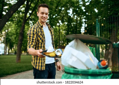 Young Volunteer Puts Trash In Plastic Bin In Park