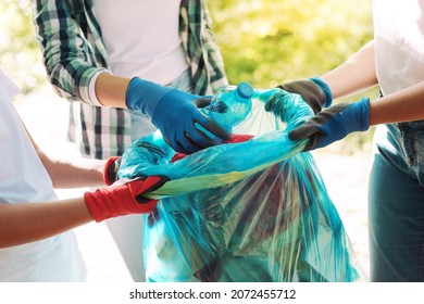 Young Volunteers Cleaning Up The City Park, They Are Putting Waste In A Garbage Bag