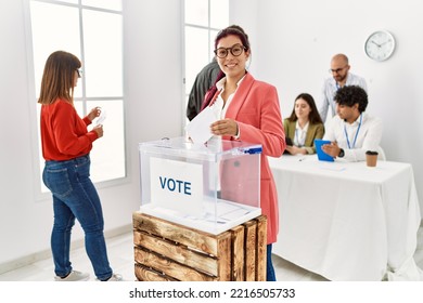 Young Voter Man Smiling Happy Putting Ballot In Voting Box At Vote Center.