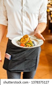 Young Waiter With Plate Full Of Tasty Dish