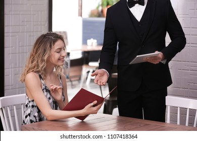 Young Waiter Taking Order From Client In Restaurant