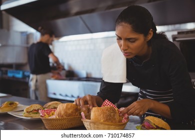 Young waitress arranging baskets with food at counter in cafe - Powered by Shutterstock