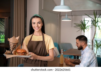 Young Waitress With Dish In Restaurant