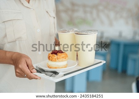 Young waitress serving scone and coffee at cafe