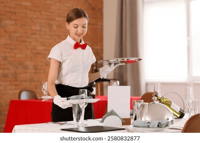Young waitress serving table in restaurant