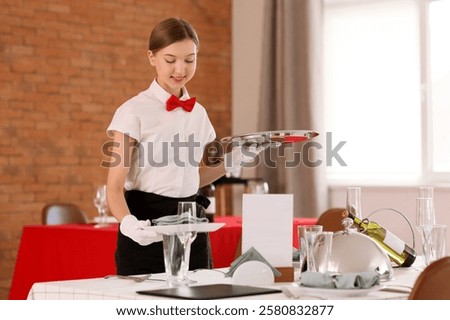 Young waitress serving table in restaurant