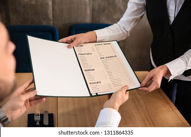 Young waitress showing man a menu in restaurant - Powered by Shutterstock