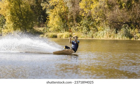 Young wakeboarder surfing along the river. Young man performing heelside edge surfing - Powered by Shutterstock