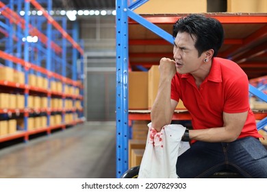 Young Warehouse Asian Worker Man Had Elbow Accident Sitting On The Floor In Warehouse Logistics Center. He Waiting For Safety Colleague Team Helping Him From Injury. First Aid Training Concept.