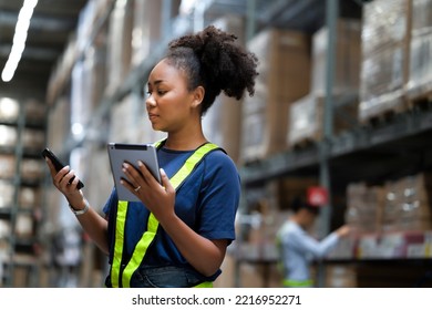 Young warehouse black worker check the message or order on smartphone and compare available stock from tablet while standing in front of shelf to inspect the boxes before pass to logistic for delivery - Powered by Shutterstock