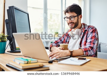 Young web designer working on code and drinking coffee in his home office