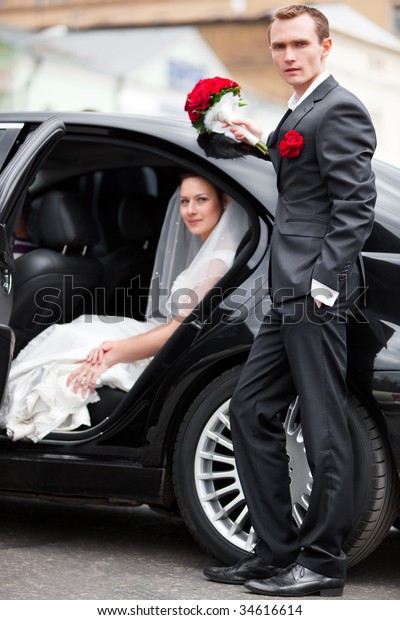 Young wedding couple at\
the luxury car.