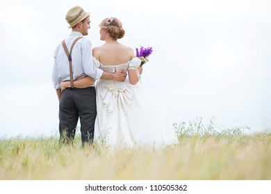 Young Wedding Couple Walking On Field.