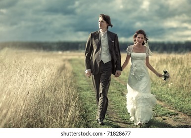 Young Wedding Couple Walking On Field.