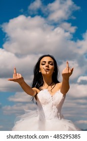young wedding sexy girl woman with brunette hair and pretty face in white bride dress showing middle fingers smoking cigarette on cloudy blue sky natural background