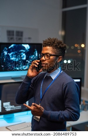 Young well-dressed programmer communicating on smartphone to one of clients of cyber security service company