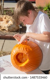 Young White Caucasian Boy Carving Pumpkin Outside