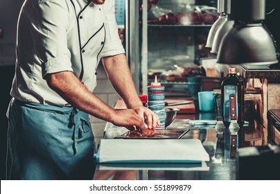 Young white chef in kitchen interior. Man marinating beef steak on a tray. Meat ready for the grill and serve. Only hands - Powered by Shutterstock