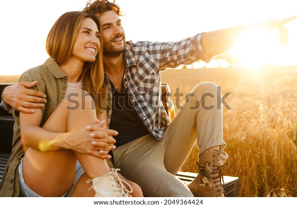 Young white couple hugging and smiling while\
sitting in trunk during\
journey