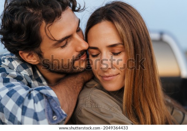 Young white couple hugging and smiling while\
sitting in trunk during\
journey