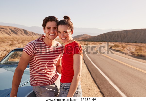 Young\
white couple on a road trip break looking to\
camera