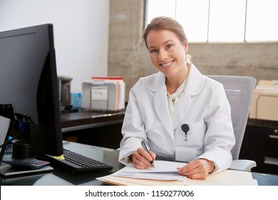 Young White Female Doctor At Desk In Office, Portrait 