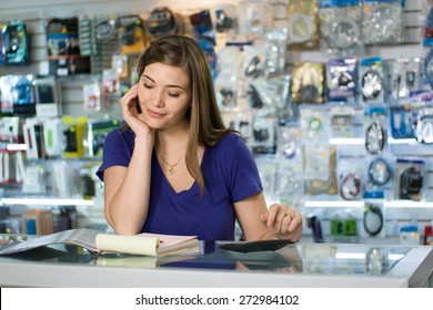 Young White Female Entrepreneur Running A Small Business And Working In A Computer Shop, And Checking Bills And Invoice With Calculator, Doing Budget And Reviewing Expenses.