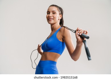 Young white fitness woman in sportswear with ponytail standing over white wall background, holding skipping rope - Shutterstock ID 1983515168