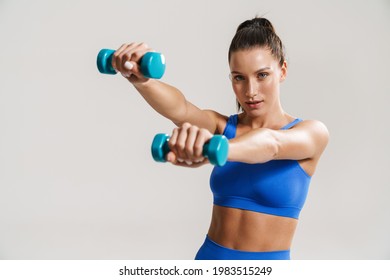 Young white fitness woman in sportswear with ponytail standing over white wall background, lifting small weights - Powered by Shutterstock