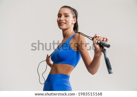 Young white fitness woman in sportswear with ponytail standing over white wall background, holding skipping rope Stock foto © 